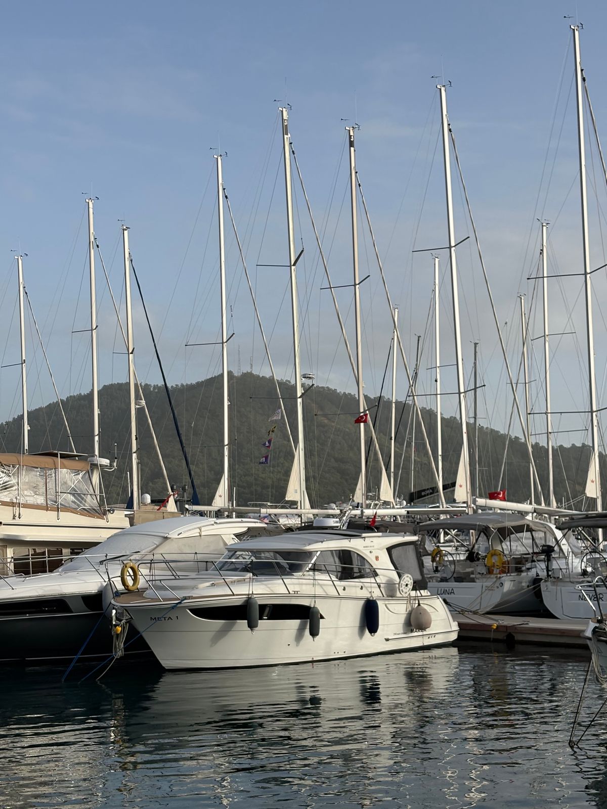 Yachts moored at Göcek marina with wooded hills behind